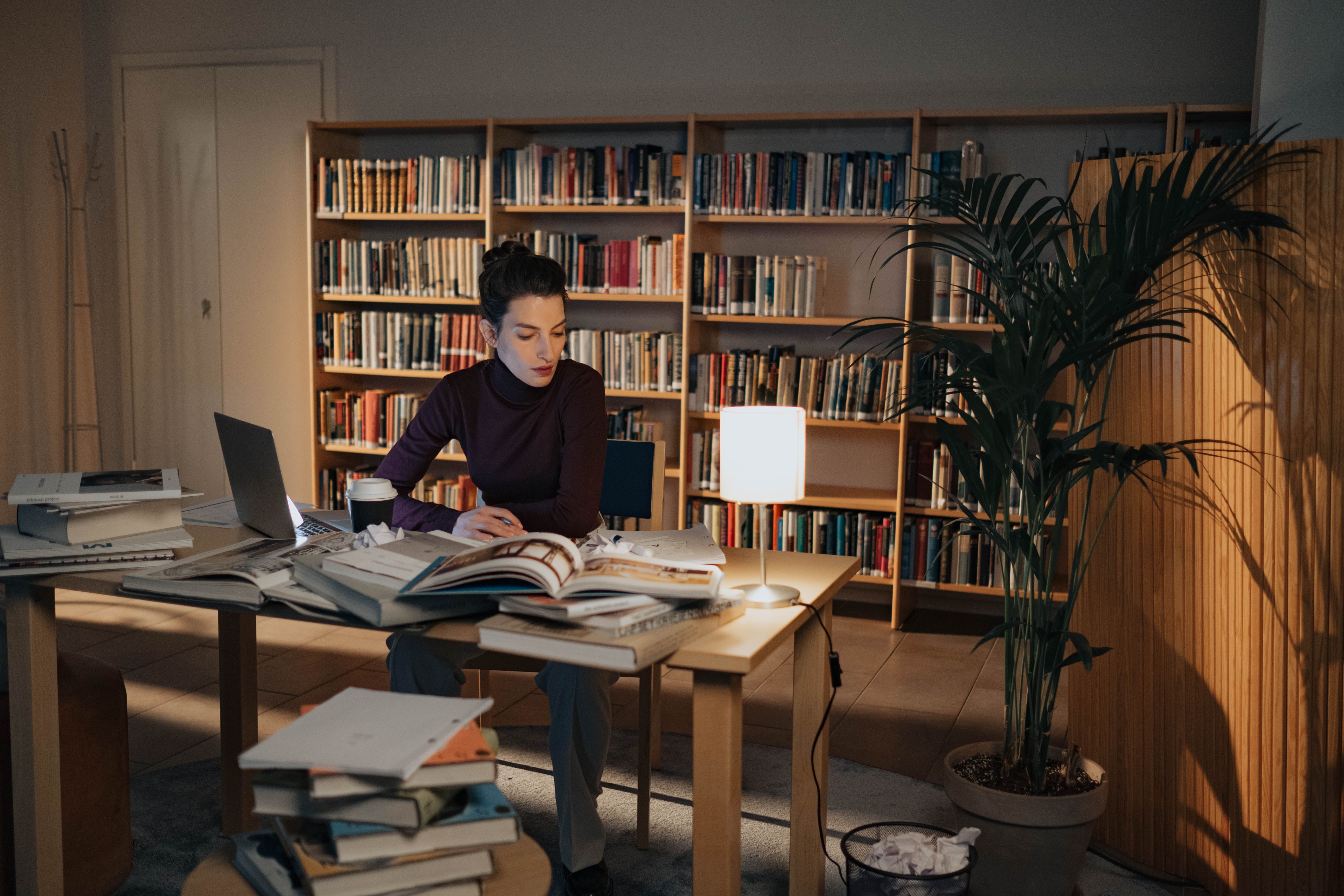 Woman researching and writing surrounded by books